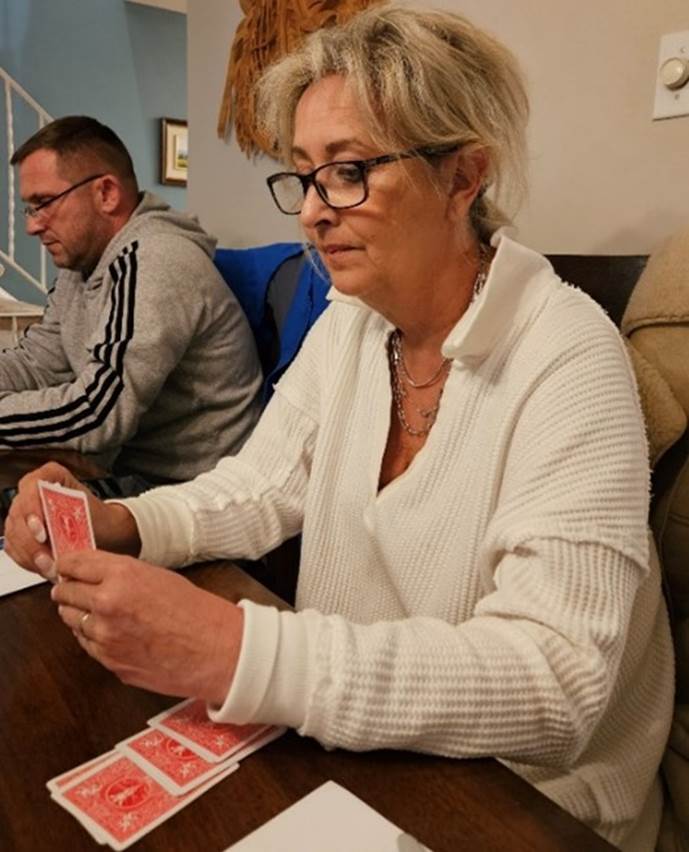 A person sitting at a table playing cards

Description automatically generated